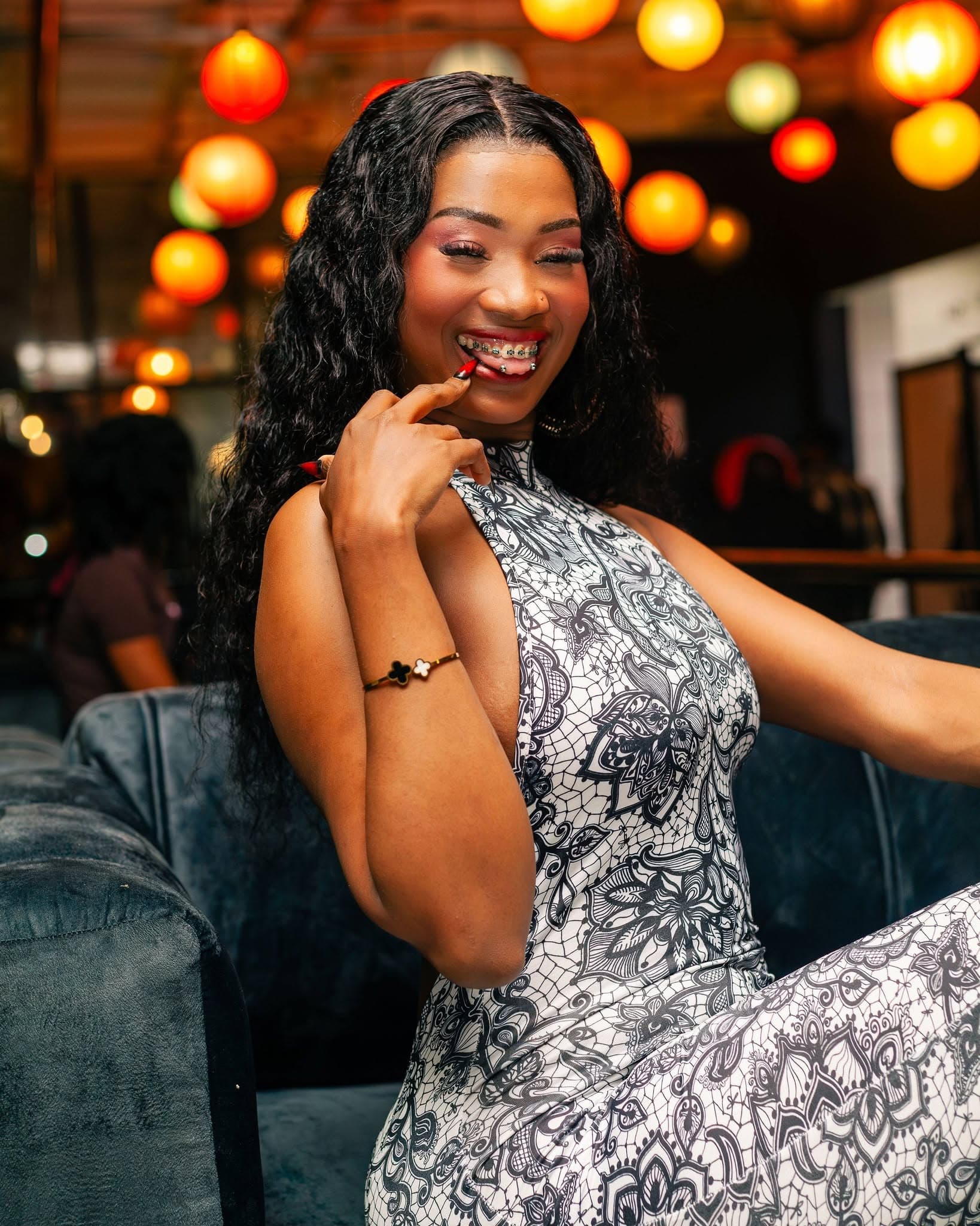 A guest laughs on the velvet lounge seating under a canopy of warm paper lanterns.