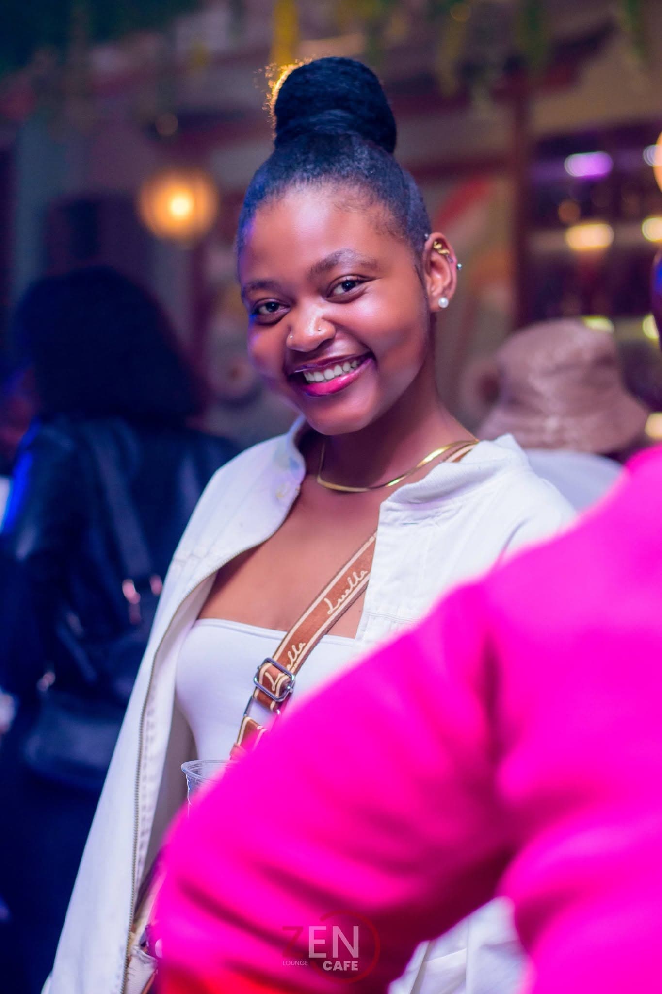A guest smiles warmly at the camera as the lounge glows softly behind her.