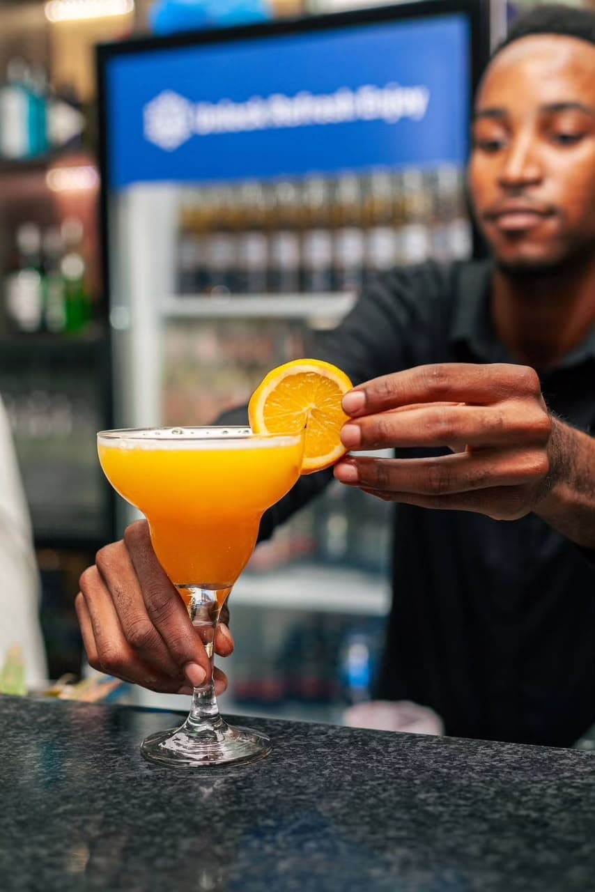 A bartender garnishes a fresh citrus cocktail with an orange slice at Zen's bar.